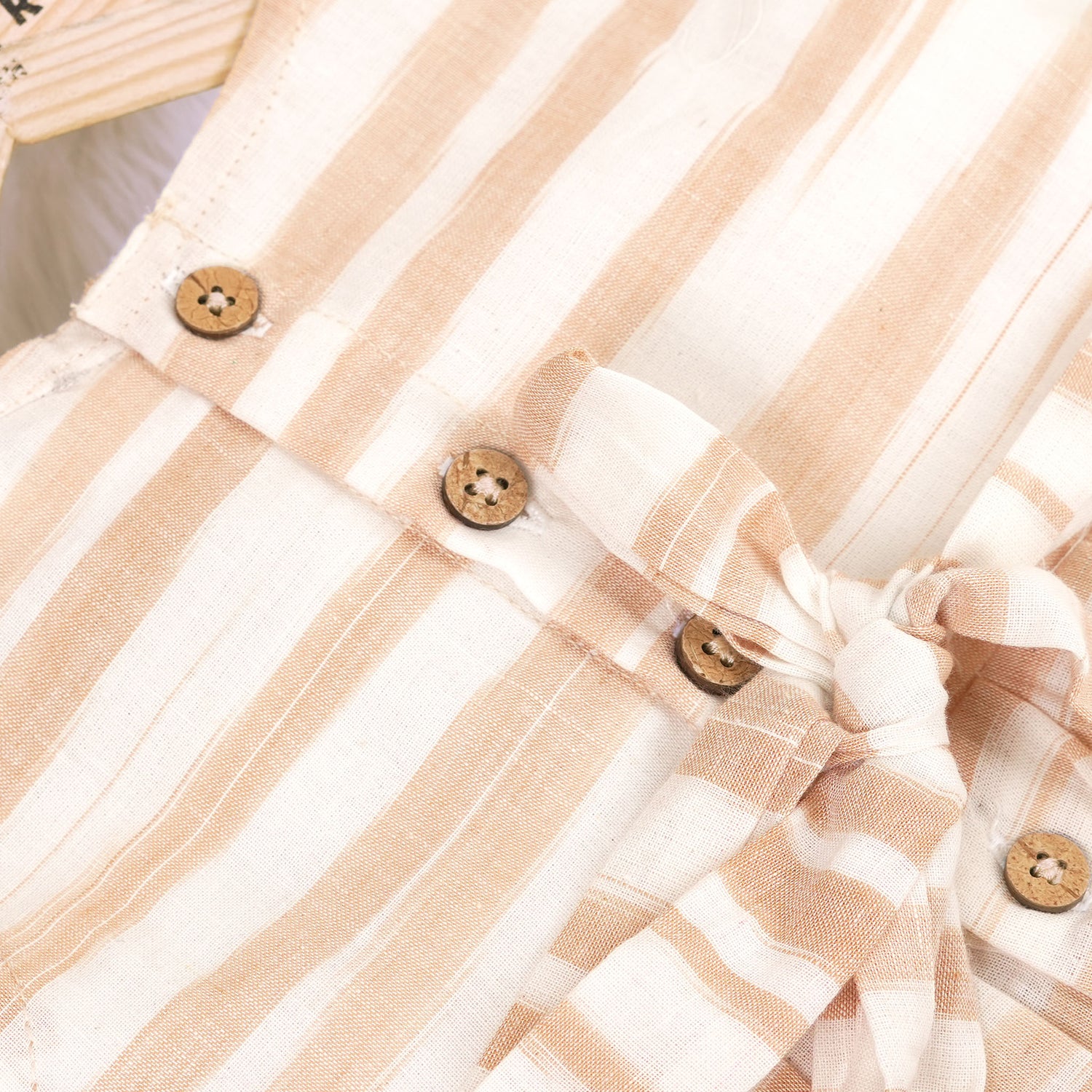 Smiling young girl wearing a sleeveless beige and white striped cotton frock from Boon Babies’ kidswear collection in Coimbatore – perfect for ages 6 months to 5 years.
