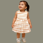 Smiling young girl wearing a sleeveless beige and white striped cotton frock from Boon Babies’ kidswear collection in Coimbatore – perfect for ages 6 months to 5 years.