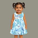 Girls' sleeveless frock in pastel blue cotton with butterfly and floral print, displayed with a wooden hanger under pink orchids – Boon Babies summer casual wear collection.
