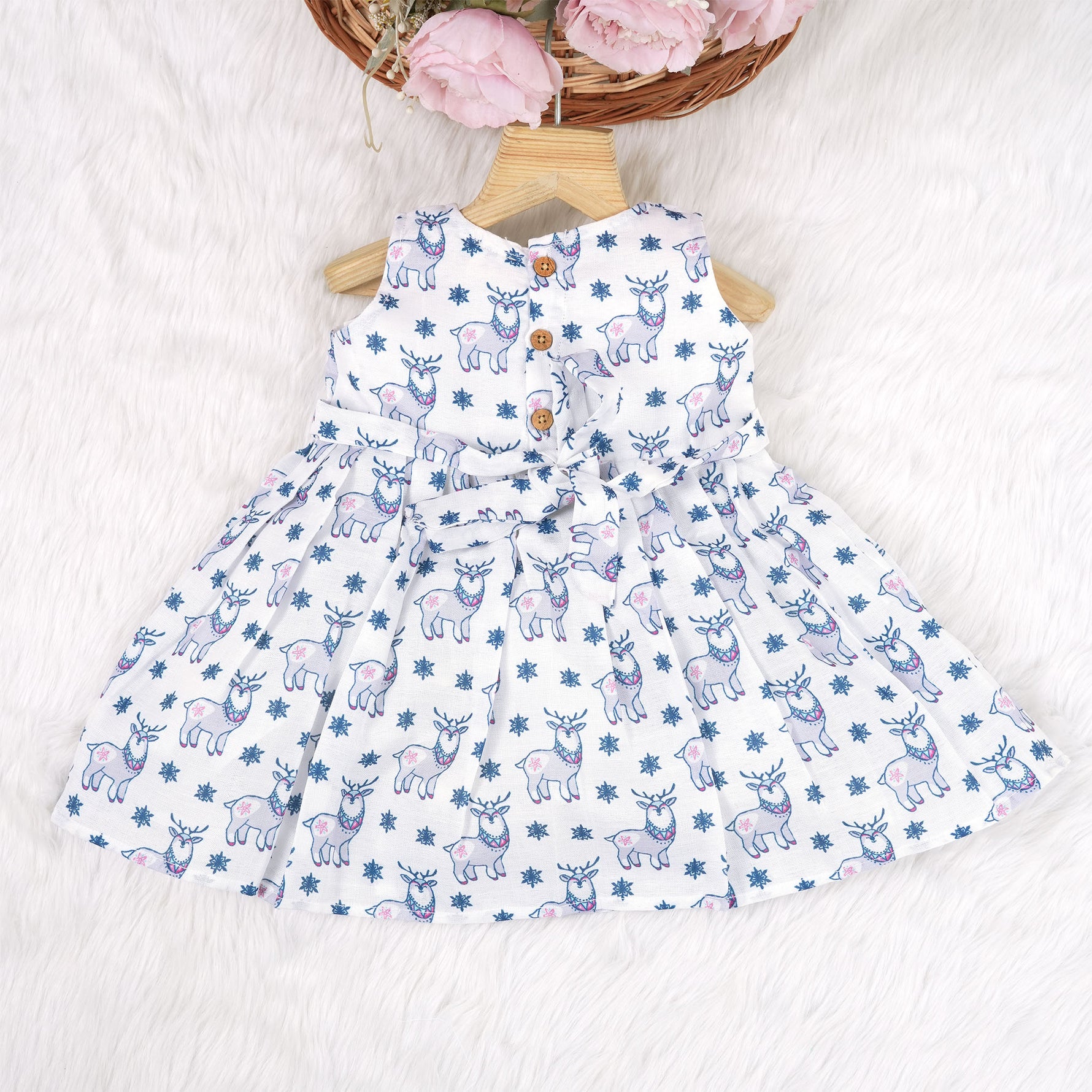 Baby girl wearing a white sleeveless frock with blue reindeer prints, made from slub cotton – part of the Boon Babies kidswear collection in Coimbatore.