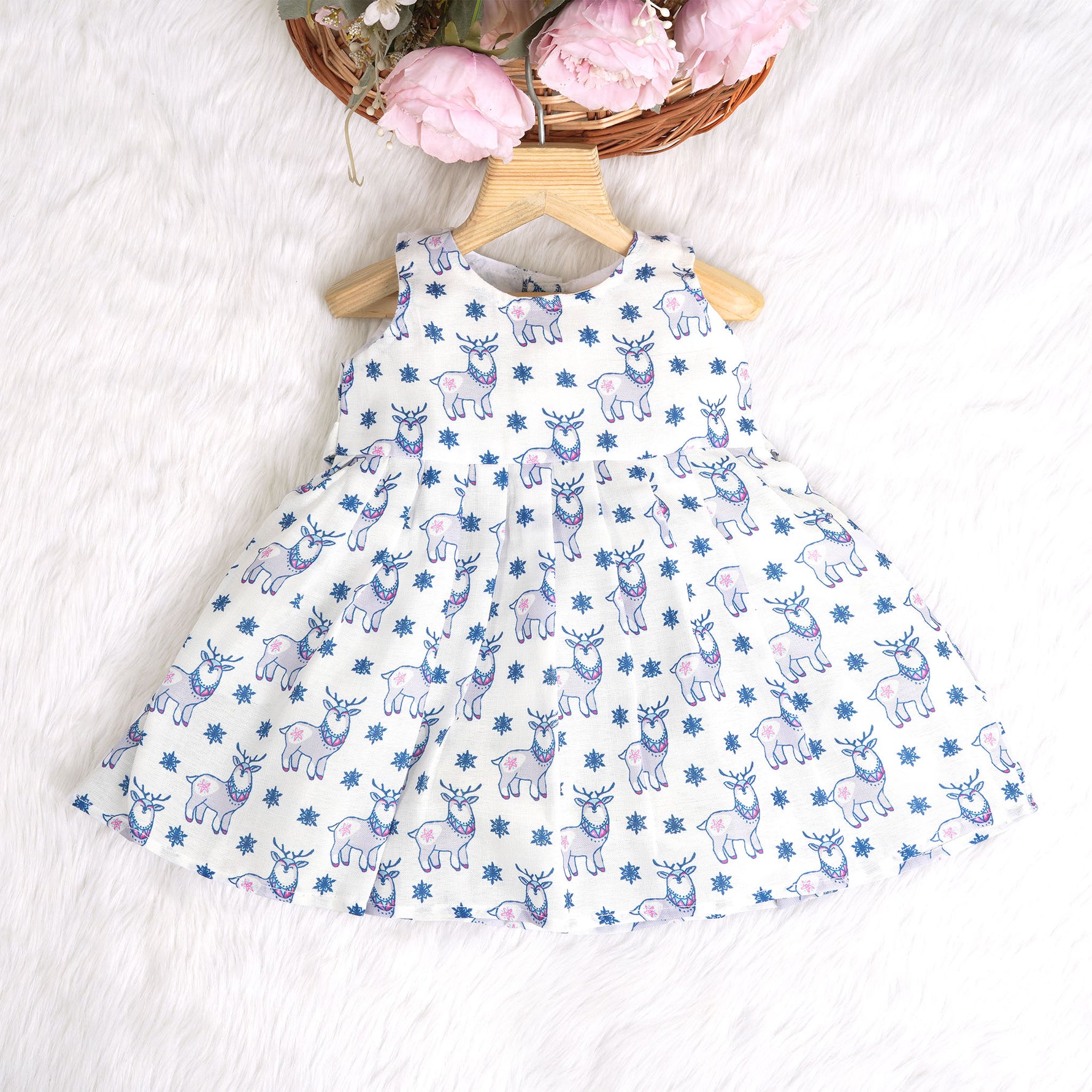 Baby girl wearing a white sleeveless frock with blue reindeer prints, made from slub cotton – part of the Boon Babies kidswear collection in Coimbatore.