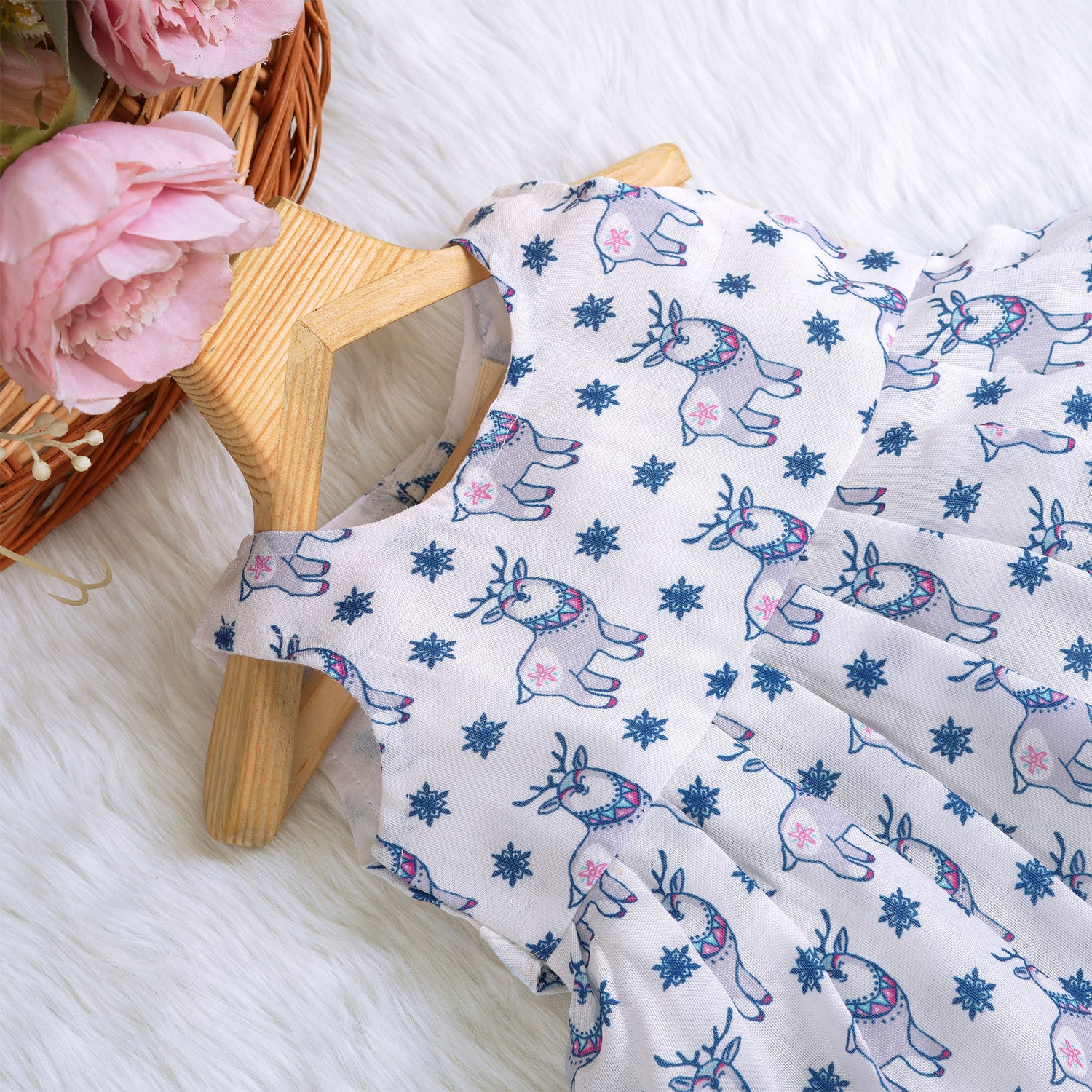 Baby girl wearing a white sleeveless frock with blue reindeer prints, made from slub cotton – part of the Boon Babies kidswear collection in Coimbatore.
