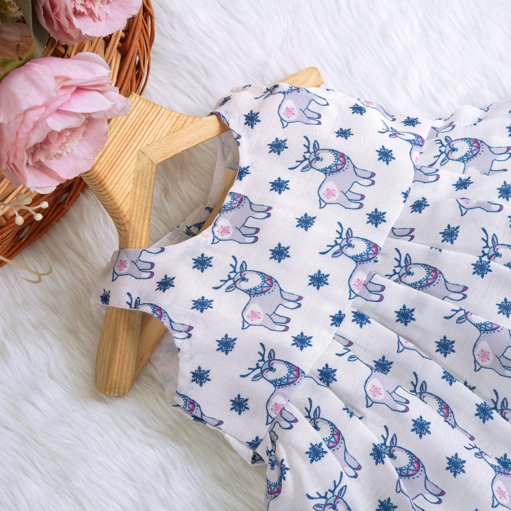 Baby girl wearing a white sleeveless frock with blue reindeer prints, made from slub cotton – part of the Boon Babies kidswear collection in Coimbatore.