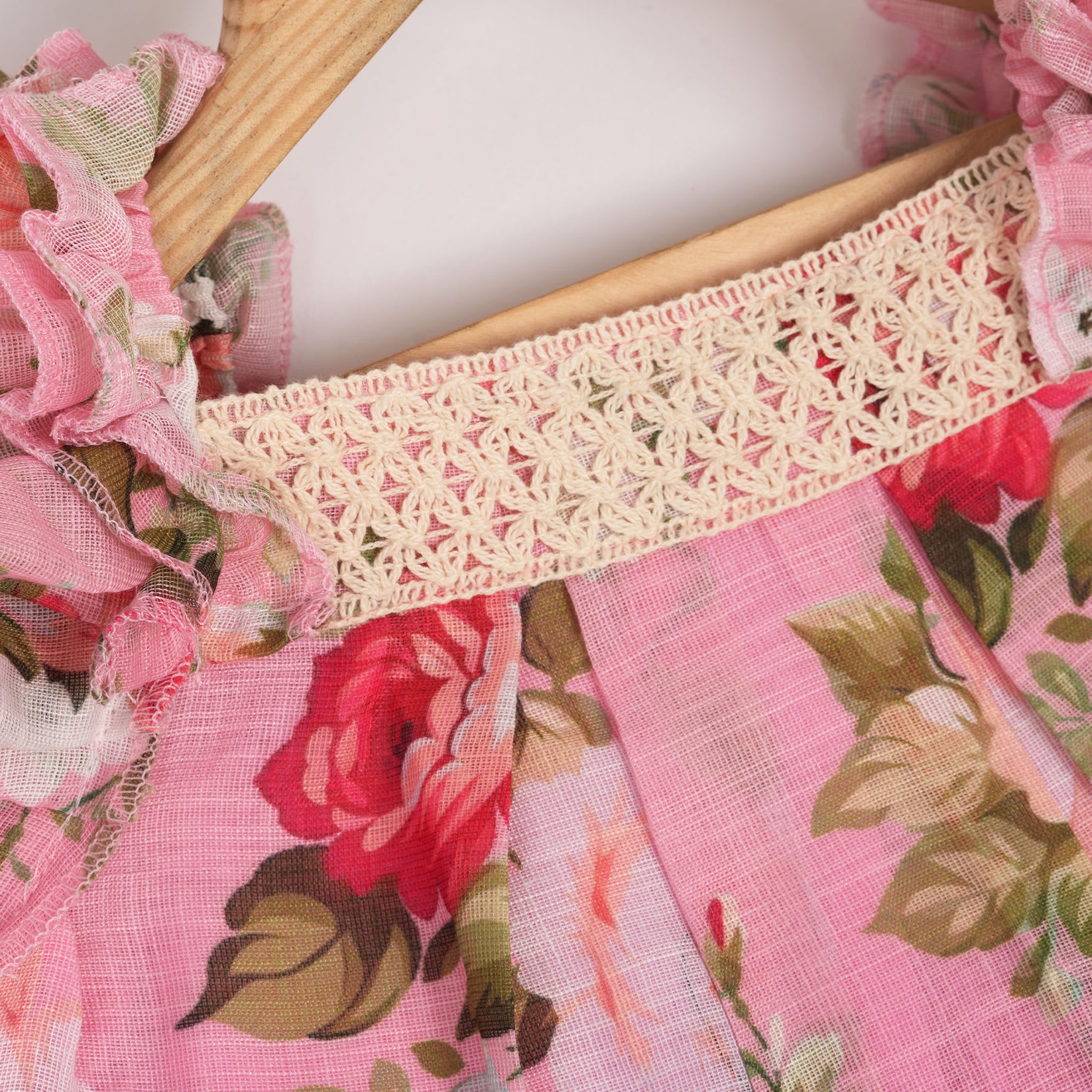 Chic dark pink linen frock with floral prints and ruffle sleeves. Sizes 6M–4Y. Ideal for festive and daily moments.
