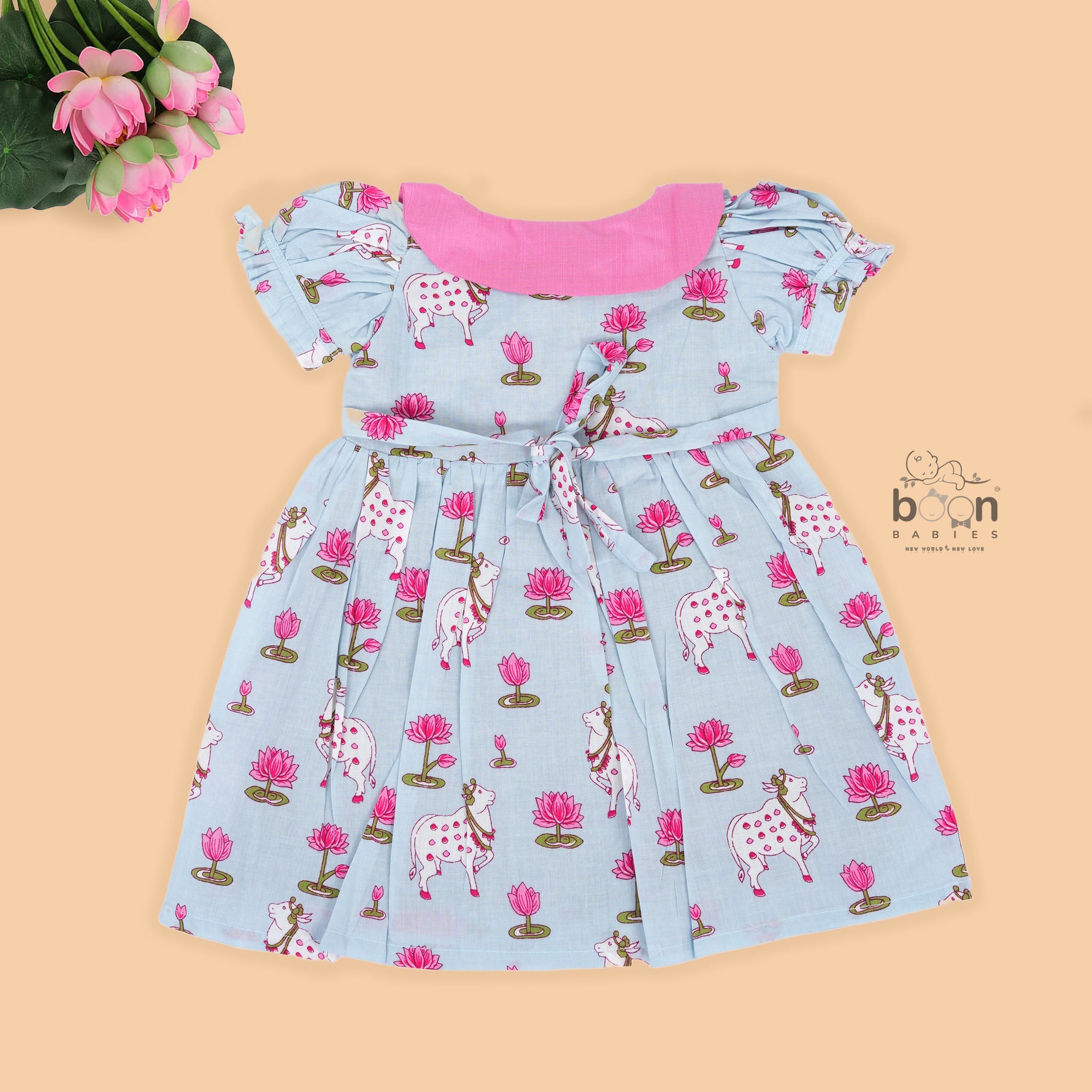 Grey cotton puff frock with pink collar, waist bow & lotus cow print. Cute & comfy for baby girls aged 6M–4Y.