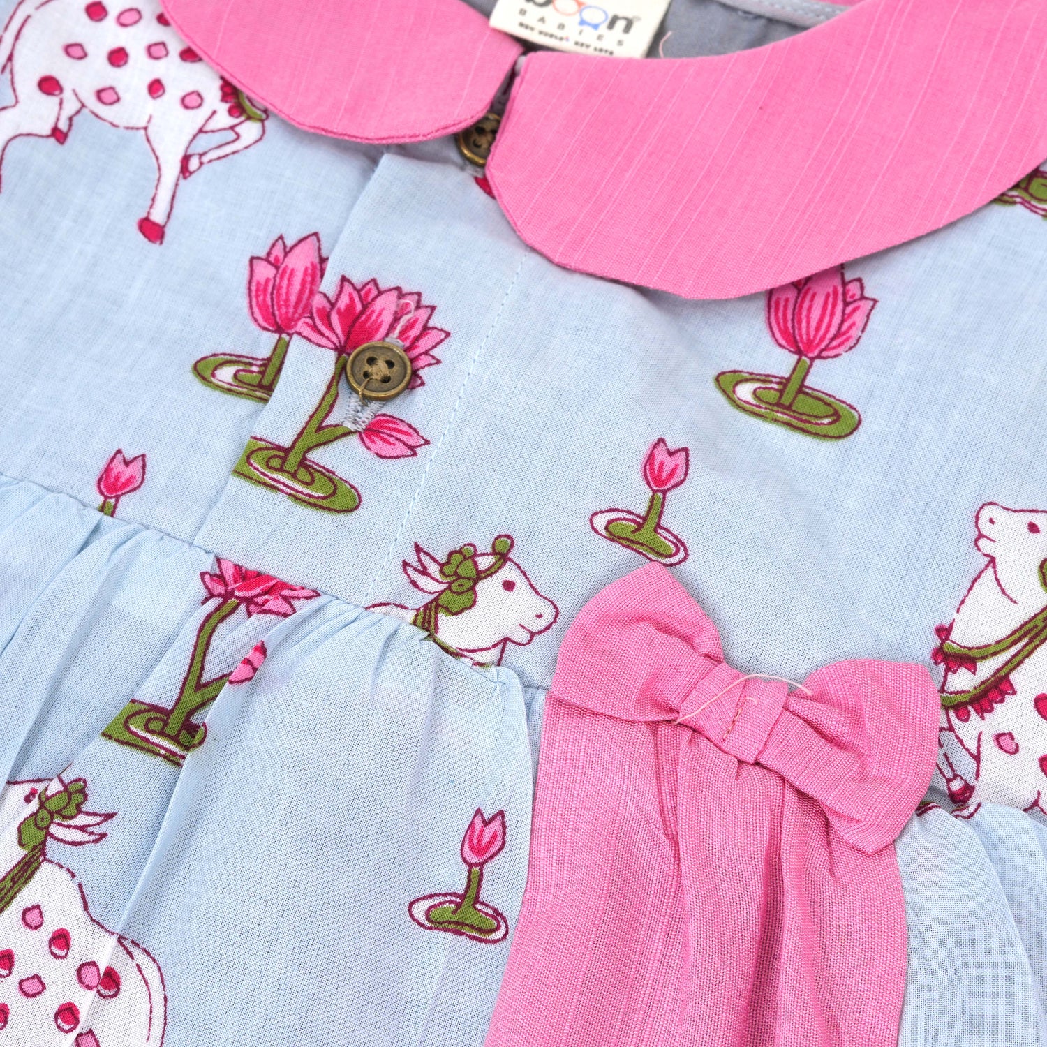 Grey cotton puff frock with pink collar, waist bow & lotus cow print. Cute & comfy for baby girls aged 6M–4Y.
