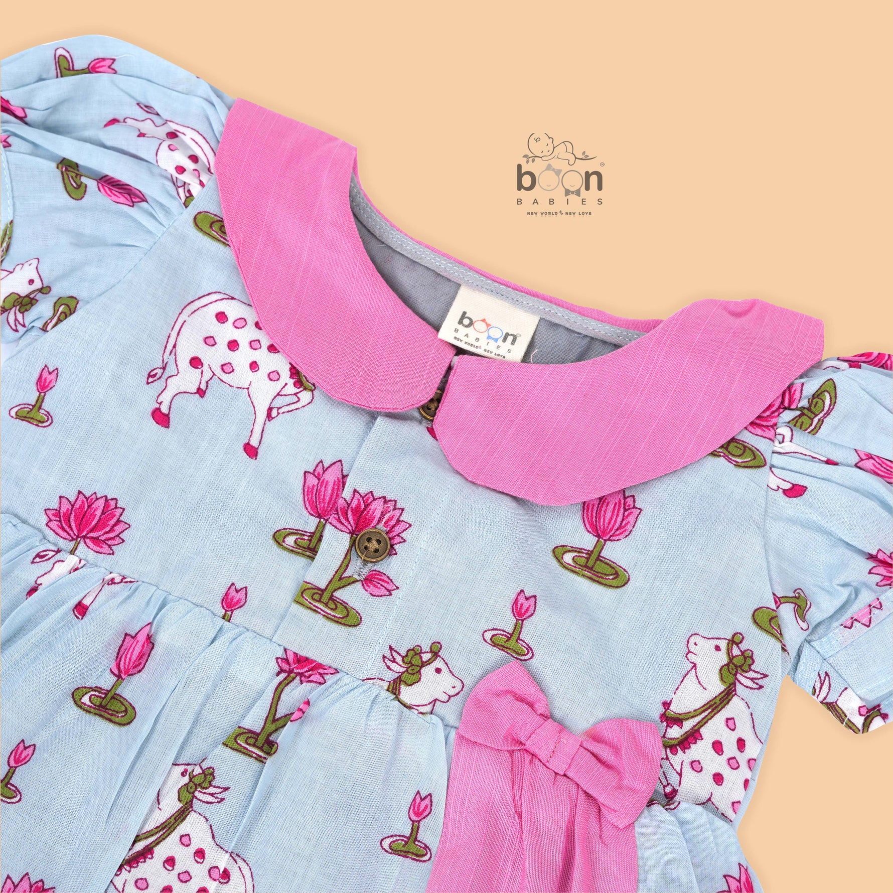 Grey cotton puff frock with pink collar, waist bow & lotus cow print. Cute & comfy for baby girls aged 6M–4Y.