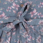 Sleeveless grey cotton frock with pink floral prints, neatly pleated and displayed on a wooden hanger under fresh orchids – from Boon Babies girlswear collection.
Sleeveless grey cotton frock with pink floral prints, neatly pleated and displayed on a wooden hanger under fresh orchids – from Boon Babies girlswear collection.
