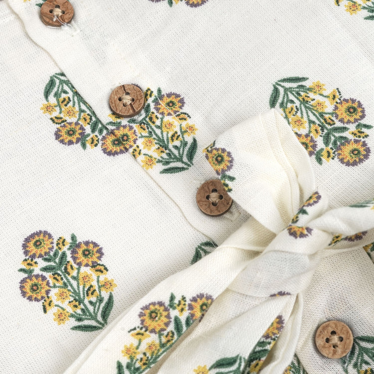 Toddler girl wearing an ivory sleeveless cotton frock with traditional floral butta print – ethnic babywear from Boon Babies, Coimbatore.