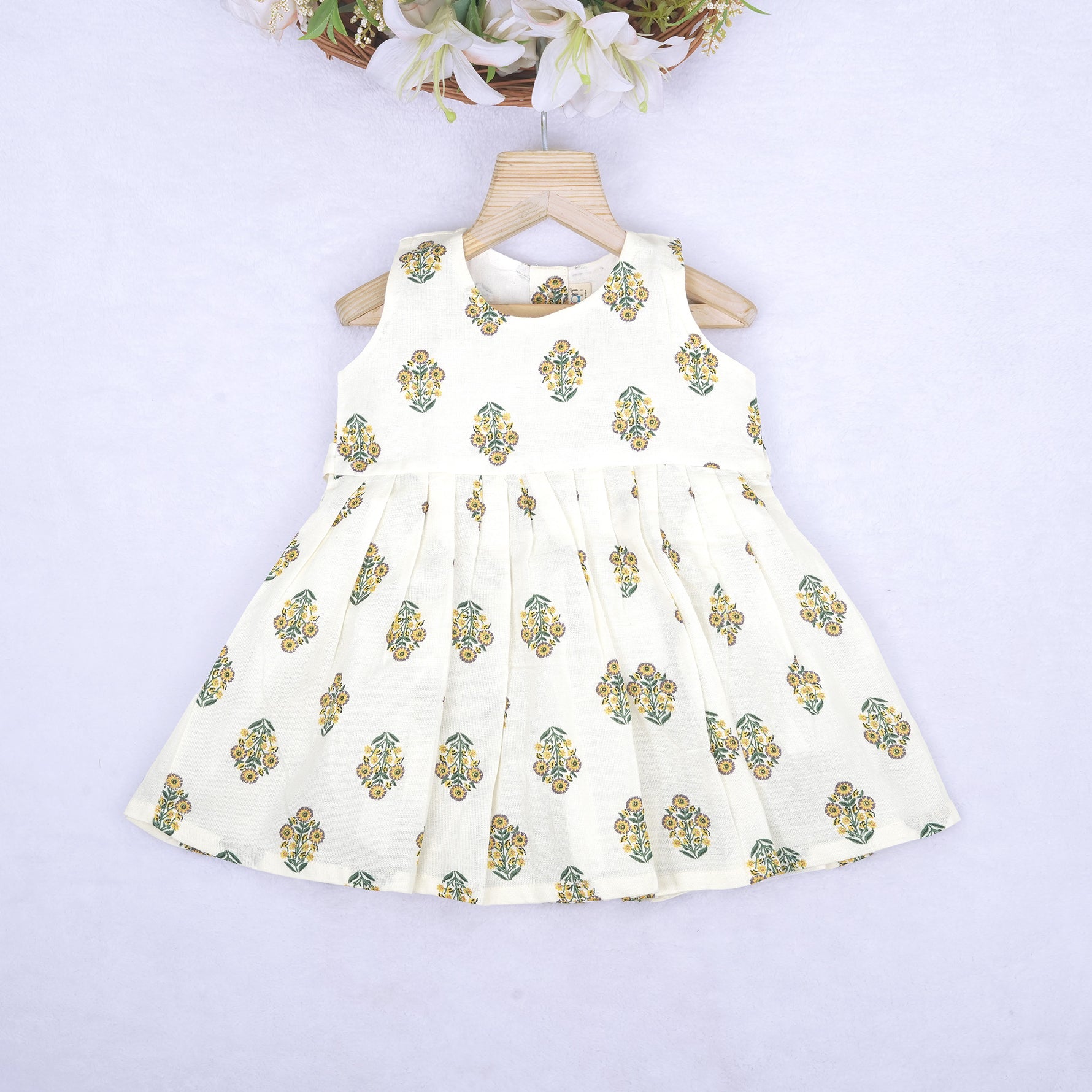 Toddler girl wearing an ivory sleeveless cotton frock with traditional floral butta print – ethnic babywear from Boon Babies, Coimbatore.