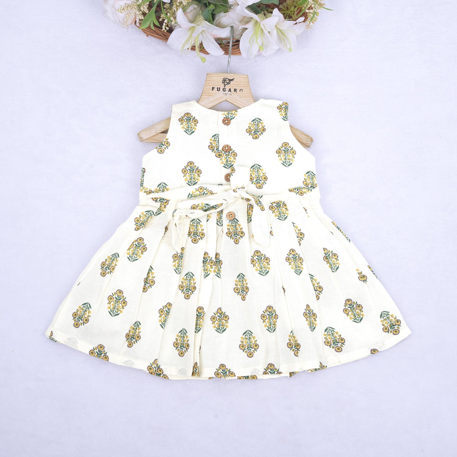 Toddler girl wearing an ivory sleeveless cotton frock with traditional floral butta print – ethnic babywear from Boon Babies, Coimbatore.
