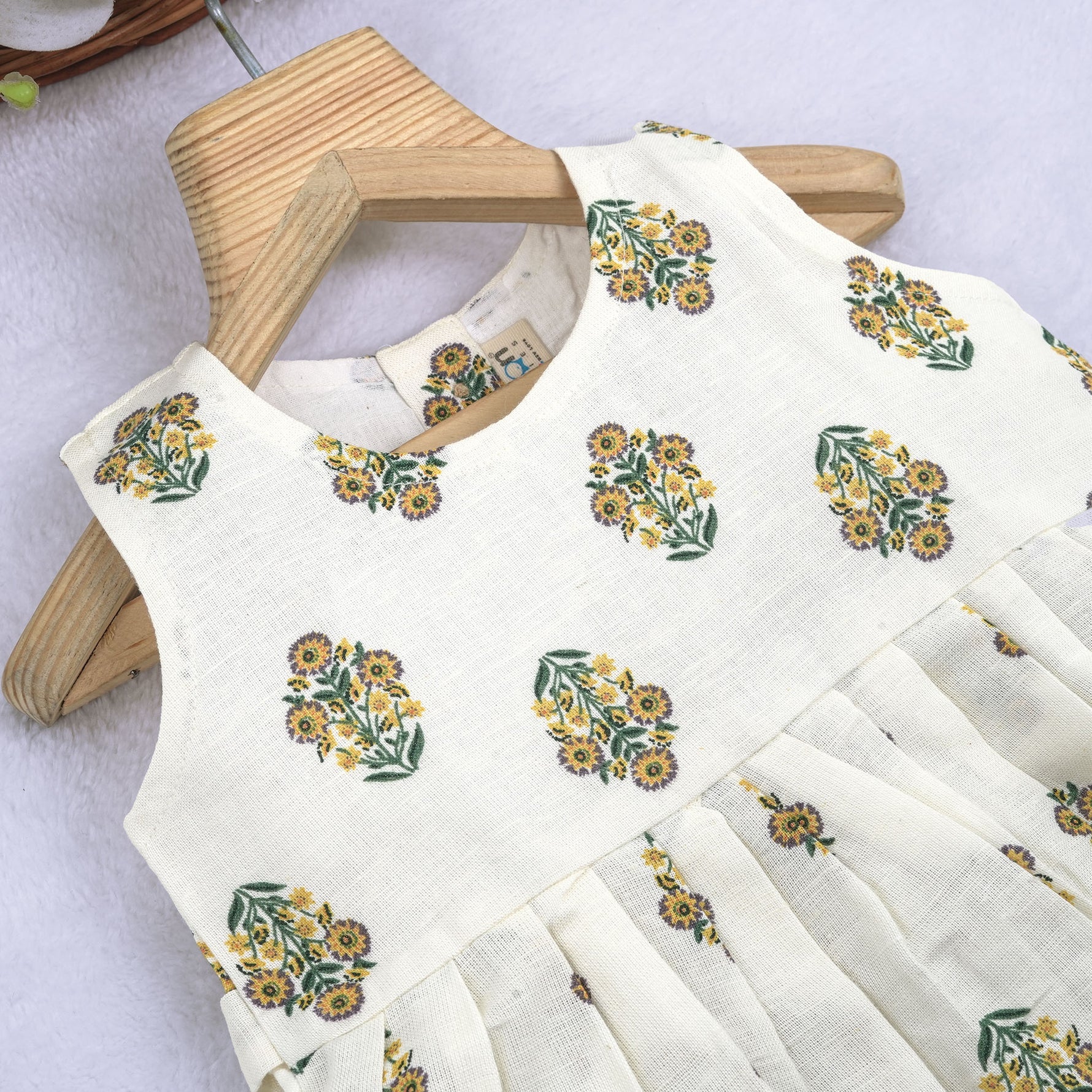 Toddler girl wearing an ivory sleeveless cotton frock with traditional floral butta print – ethnic babywear from Boon Babies, Coimbatore.
