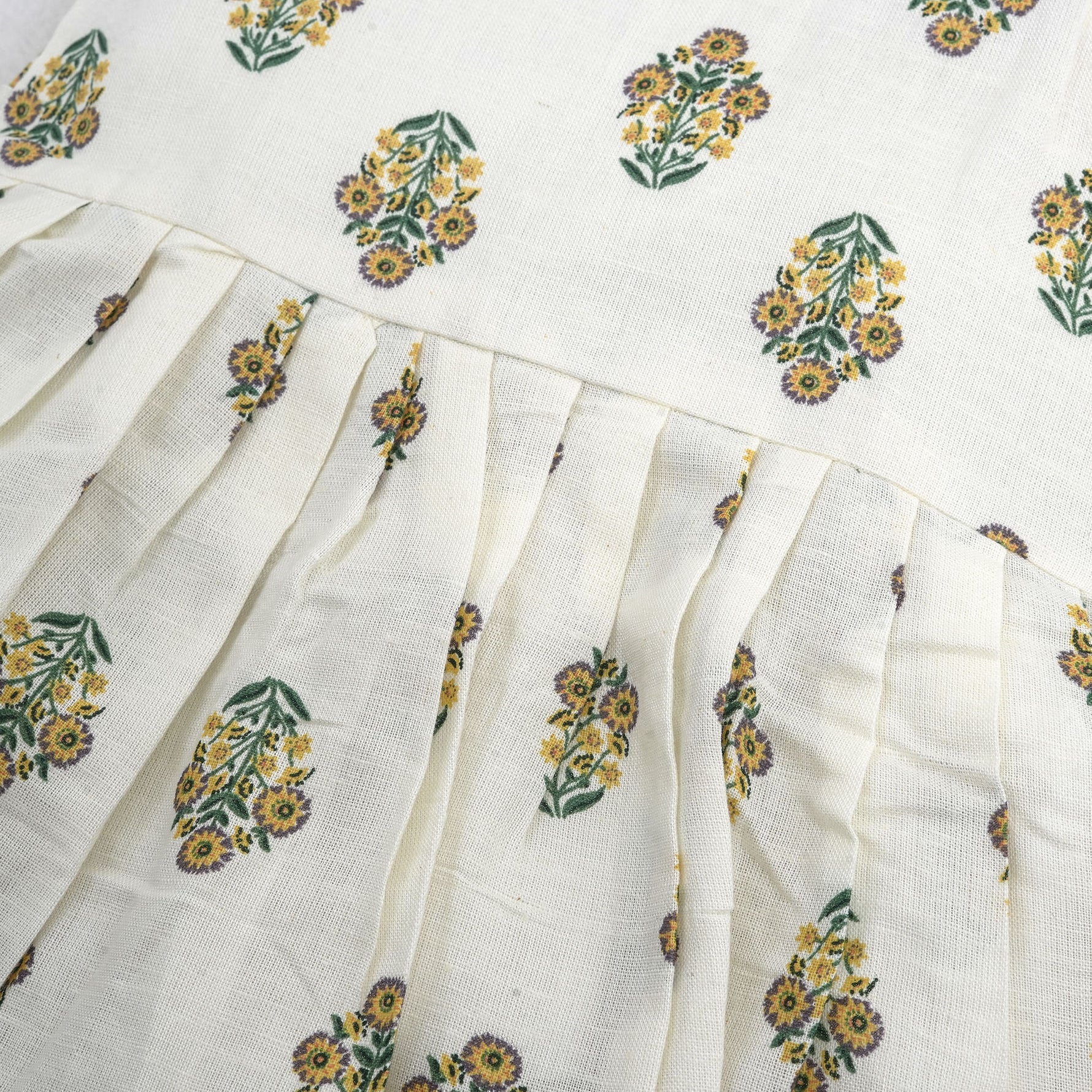 Toddler girl wearing an ivory sleeveless cotton frock with traditional floral butta print – ethnic babywear from Boon Babies, Coimbatore.