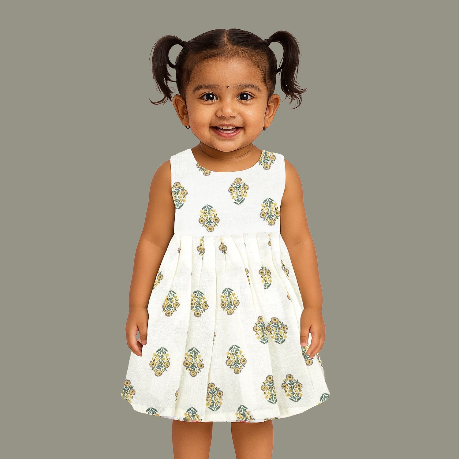 Toddler girl wearing an ivory sleeveless cotton frock with traditional floral butta print – ethnic babywear from Boon Babies, Coimbatore.