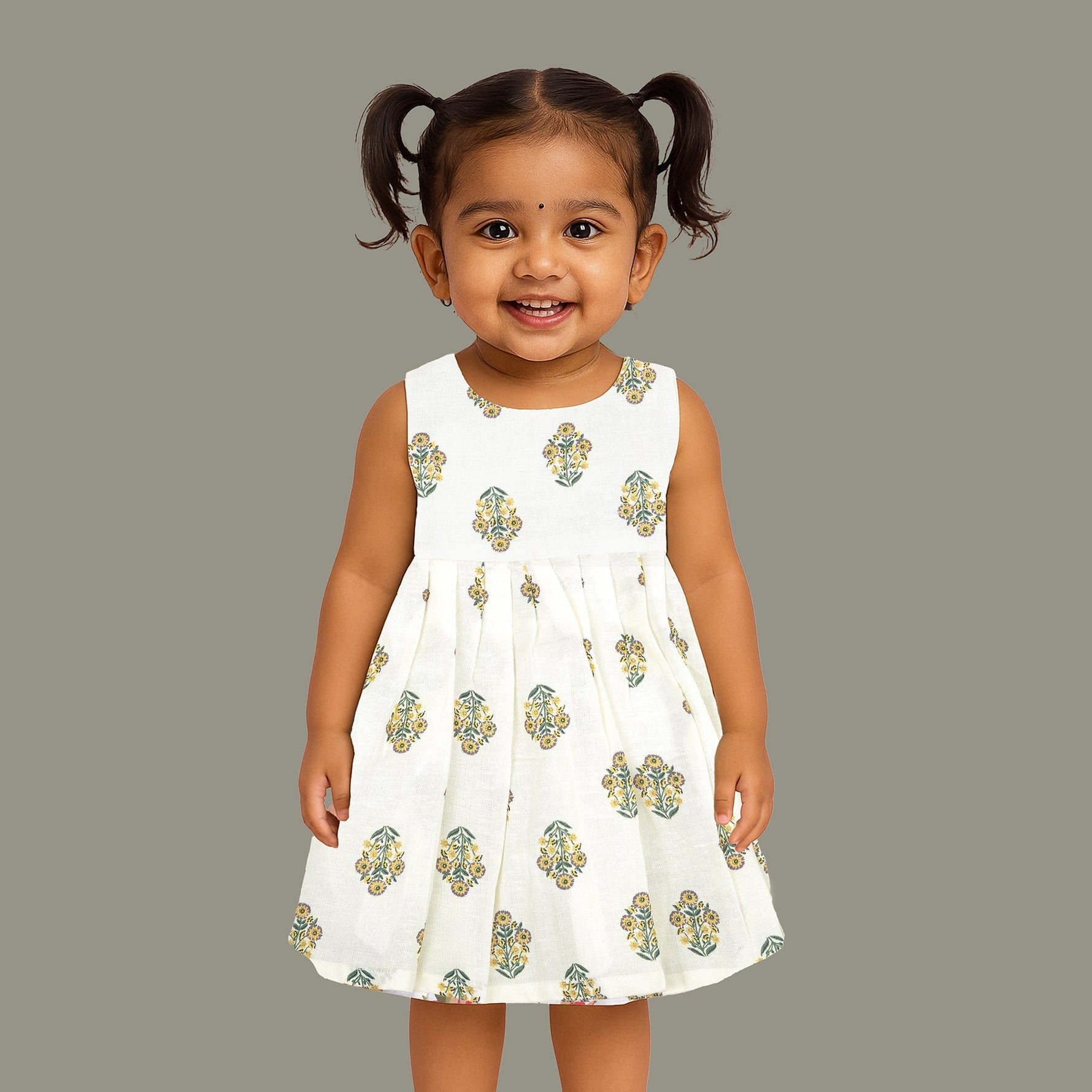 Toddler girl wearing an ivory sleeveless cotton frock with traditional floral butta print – ethnic babywear from Boon Babies, Coimbatore.