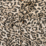 Leopard print sleeveless cotton frock for girls aged 12M–5Y, with a flared pleated skirt – displayed on a wooden hanger with white roses in the background.