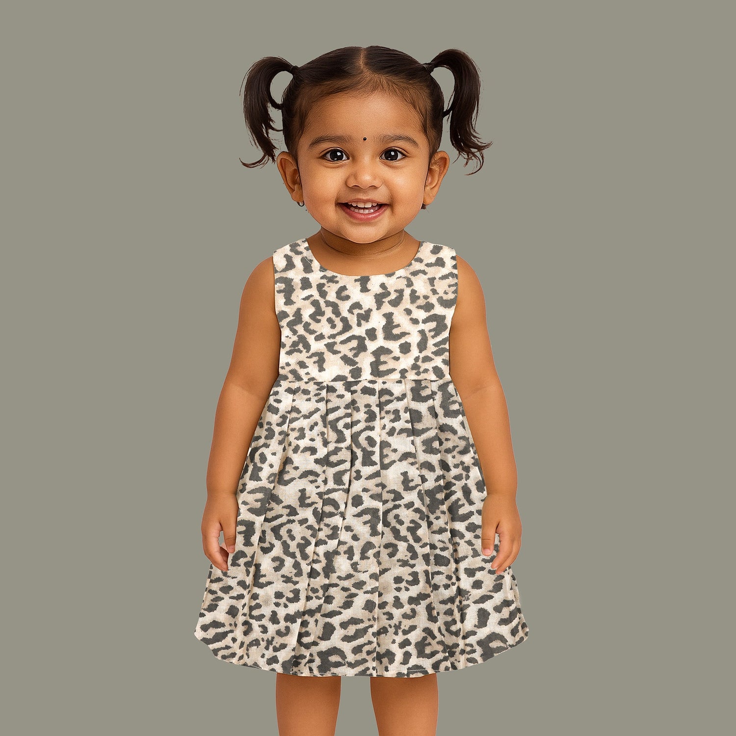Leopard print sleeveless cotton frock for girls aged 12M–5Y, with a flared pleated skirt – displayed on a wooden hanger with white roses in the background.