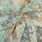 Mint green floral sleeveless chiffon cotton frock for baby girls, pleated and lightweight, displayed on a wooden hanger over a white fur backdrop with pink and white flowers.