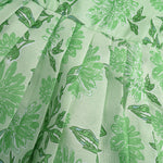 Mint green floral printed sleeveless slub cotton frock for baby girls with pleated flare, displayed flat on white fur background with floral basket hanger.