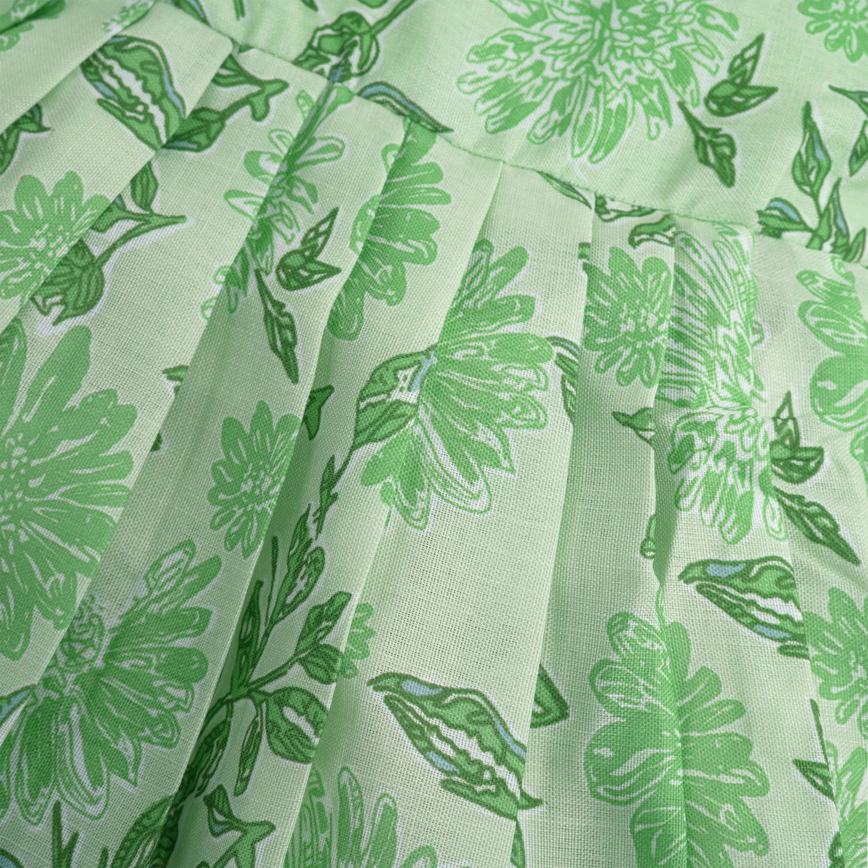 Mint green floral printed sleeveless slub cotton frock for baby girls with pleated flare, displayed flat on white fur background with floral basket hanger.