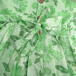 Mint green floral printed sleeveless slub cotton frock for baby girls with pleated flare, displayed flat on white fur background with floral basket hanger.