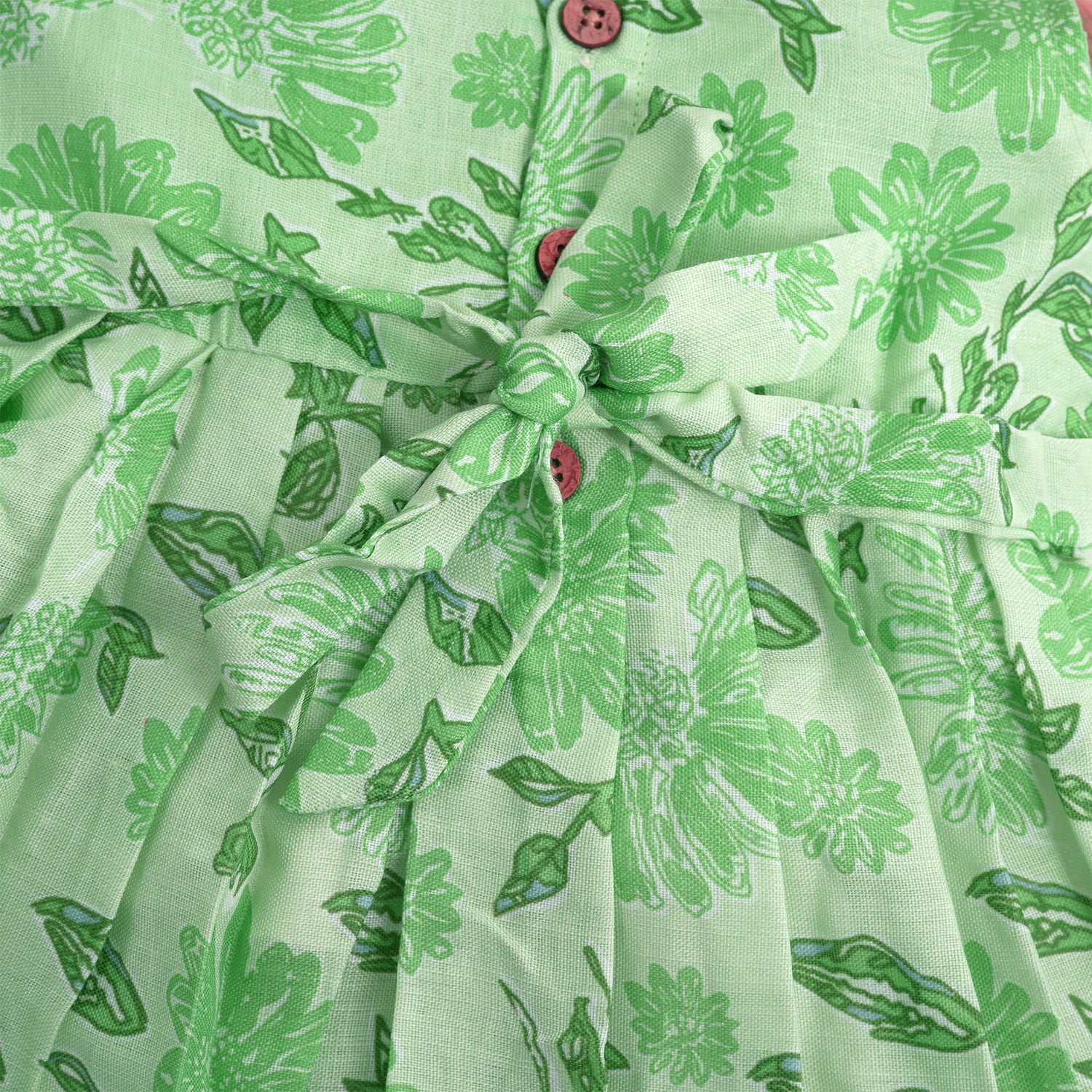 Mint green floral printed sleeveless slub cotton frock for baby girls with pleated flare, displayed flat on white fur background with floral basket hanger.