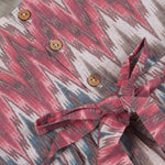 Girls’ sleeveless frock in multicolor Ikat print, made from cotton – displayed flat on white fur background with floral props – Boon Babies casual summer wear for girls aged 12M to 5Y.
