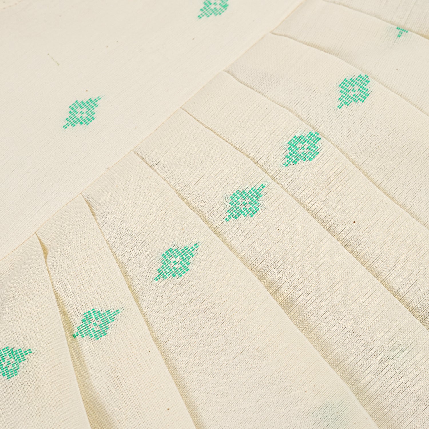 Pastel yellow sleeveless cotton frock with mint green embroidery and pleated skirt for baby girls, displayed on a white fur background with floral basket hanger.