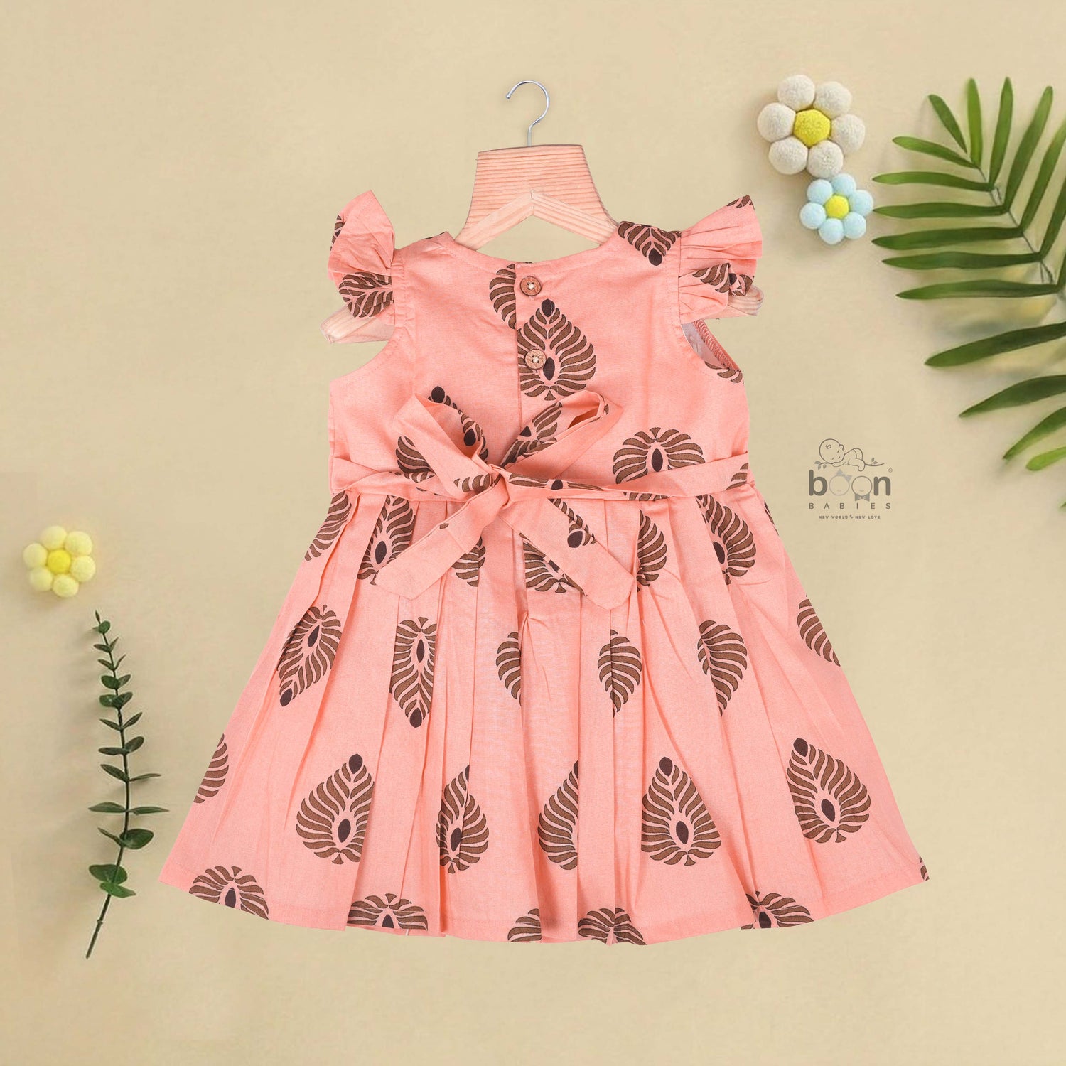 Peach cotton frock with bold leaf print and flutter sleeves. Made for girls aged 6 months to 5 years. Soft, breathable, and perfect for summer wear.
