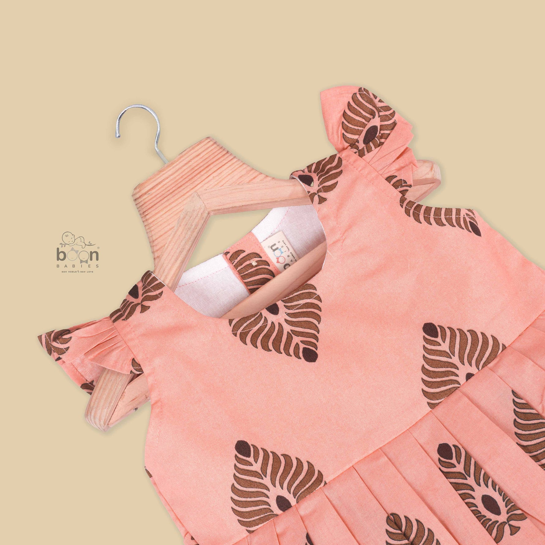 Peach cotton frock with bold leaf print and flutter sleeves. Made for girls aged 6 months to 5 years. Soft, breathable, and perfect for summer wear.
