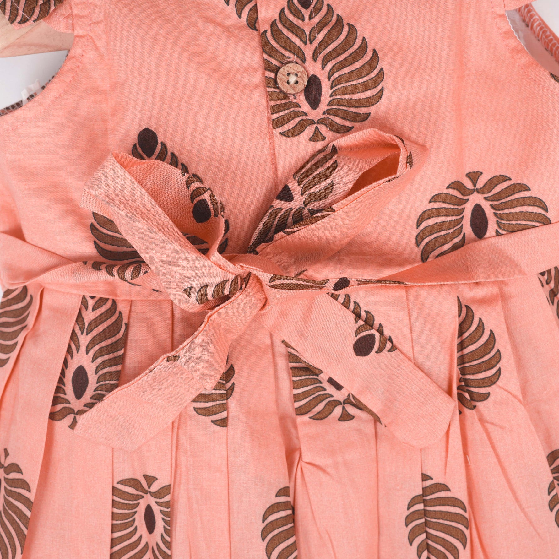 Peach cotton frock with bold leaf print and flutter sleeves. Made for girls aged 6 months to 5 years. Soft, breathable, and perfect for summer wear.
