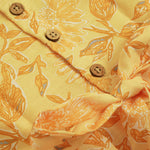 Sunshine yellow sleeveless slub cotton frock for baby girls with all-over orange floral print and pleated skirt, displayed flat on a white fur background with floral basket hanger.