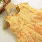 Sunshine yellow sleeveless slub cotton frock for baby girls with all-over orange floral print and pleated skirt, displayed flat on a white fur background with floral basket hanger.