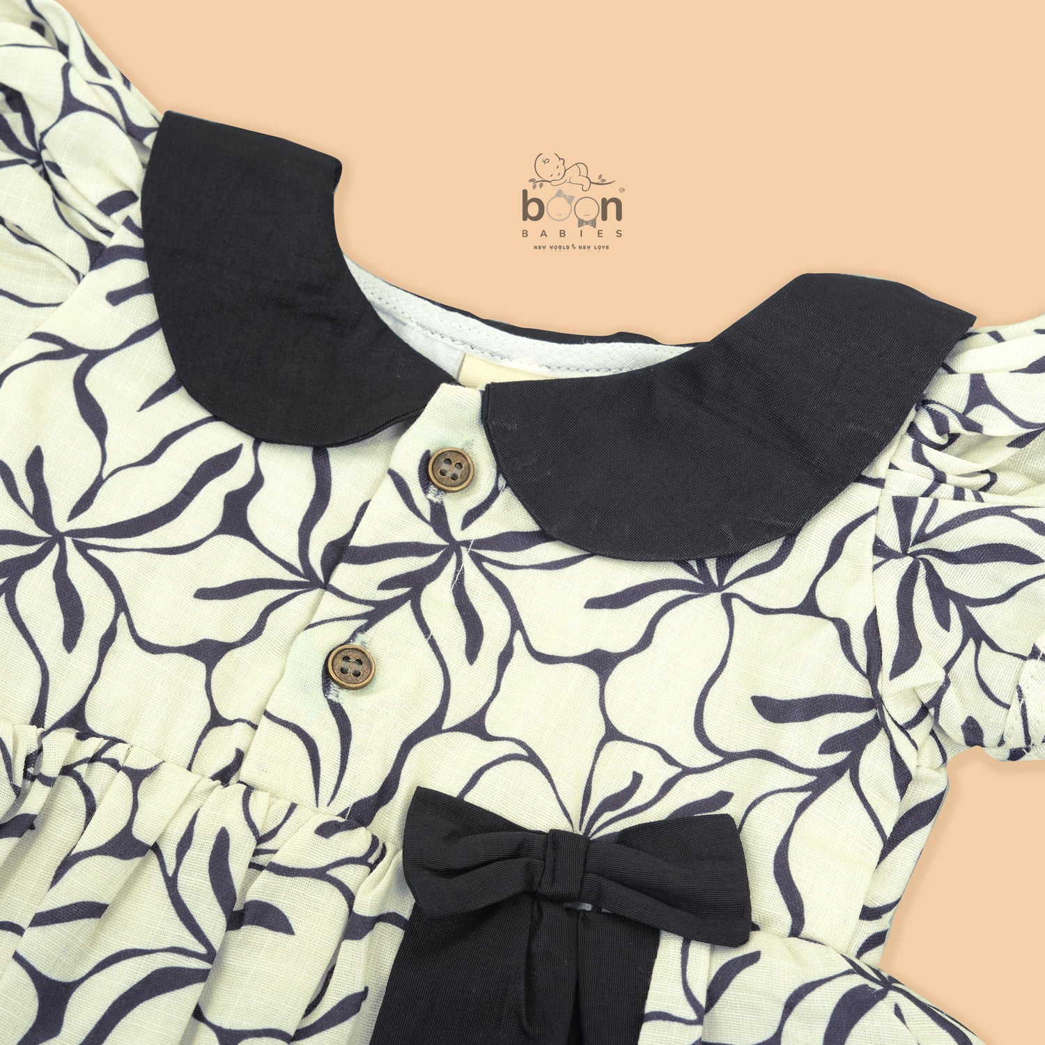 Black & white cotton Side Pleated Frock with floral print, contrast collar & bow detail. Stylish & comfy for baby girls aged 6M–4Y.