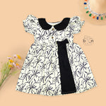 Black & white cotton Side Pleated Frock with floral print, contrast collar & bow detail. Stylish & comfy for baby girls aged 6M–4Y.