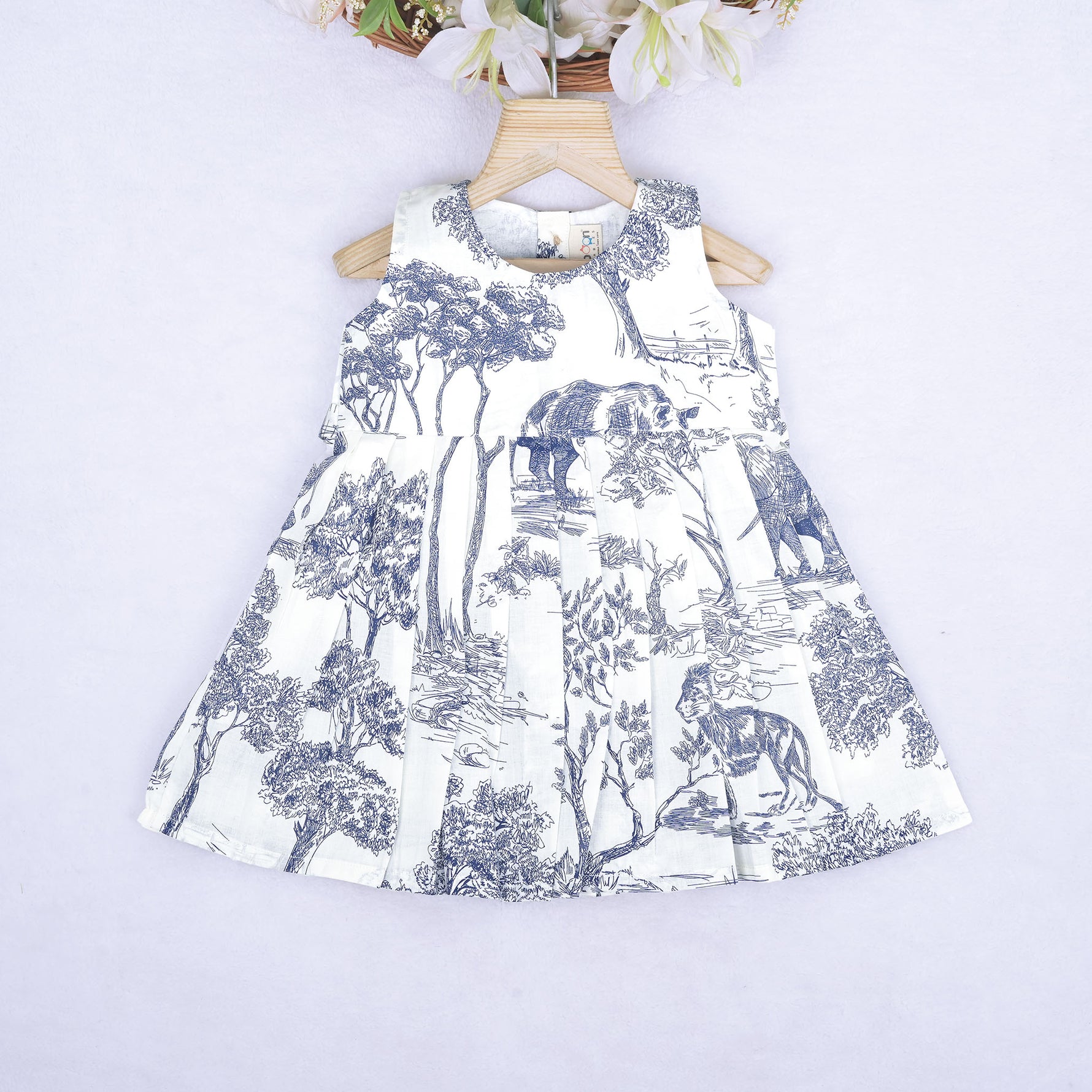 Toddler girl wearing a white and blue sleeveless cotton frock with forest and elephant print – soft summer wear from Boon Babies, Coimbatore.
