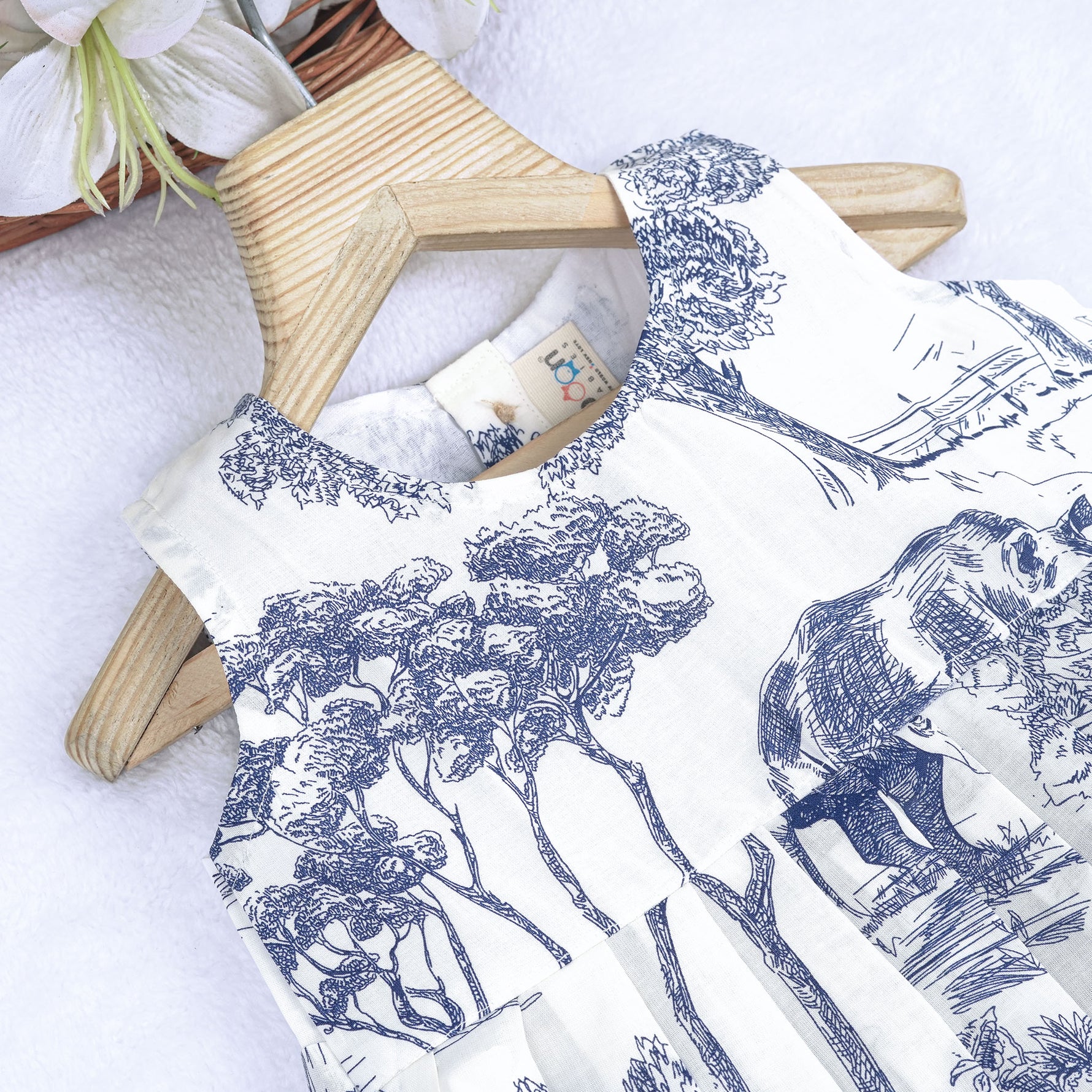 Toddler girl wearing a white and blue sleeveless cotton frock with forest and elephant print – soft summer wear from Boon Babies, Coimbatore.