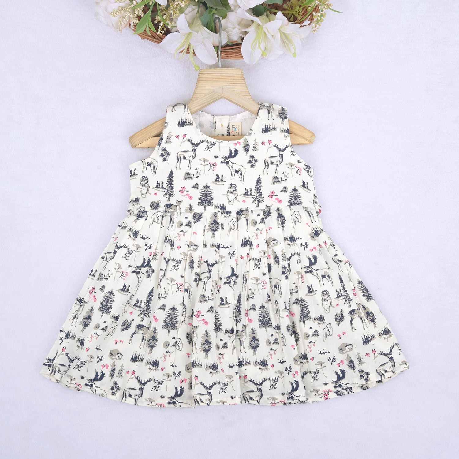 Toddler girl wearing a sleeveless white cotton frock with pink and green floral print – lightweight summer dress from Boon Babies, Coimbatore.
