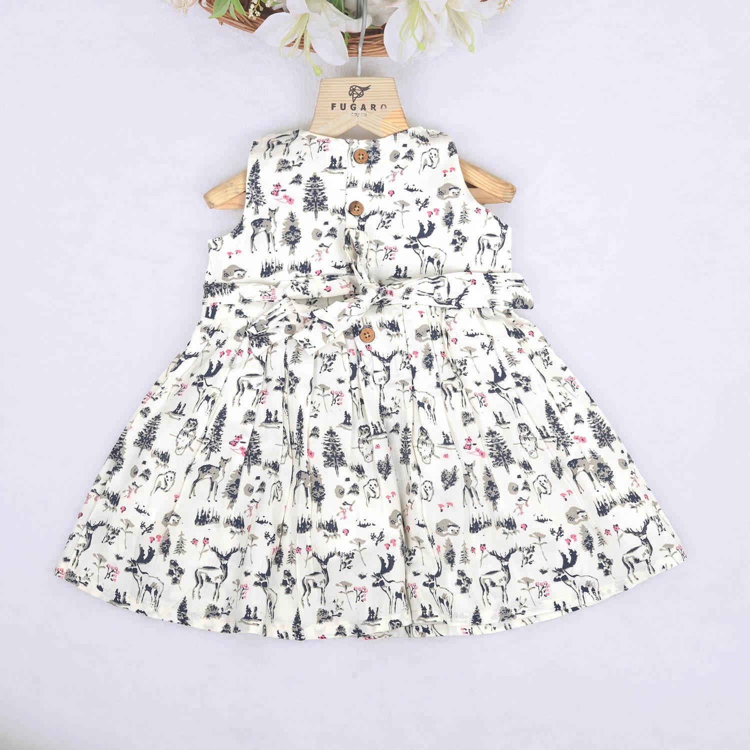Toddler girl wearing a sleeveless white cotton frock with pink and green floral print – lightweight summer dress from Boon Babies, Coimbatore.