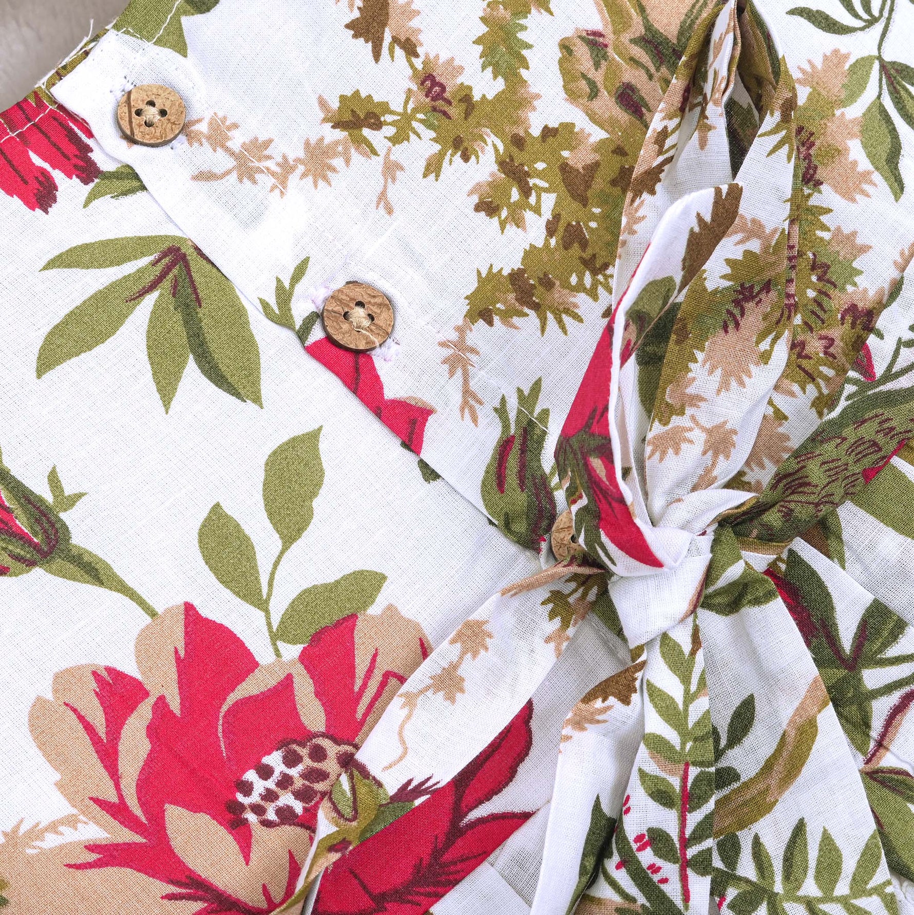 Toddler girl wearing a sleeveless white cotton frock with large pink floral and olive green leaf print – soft summer dress from Boon Babies, Coimbatore.