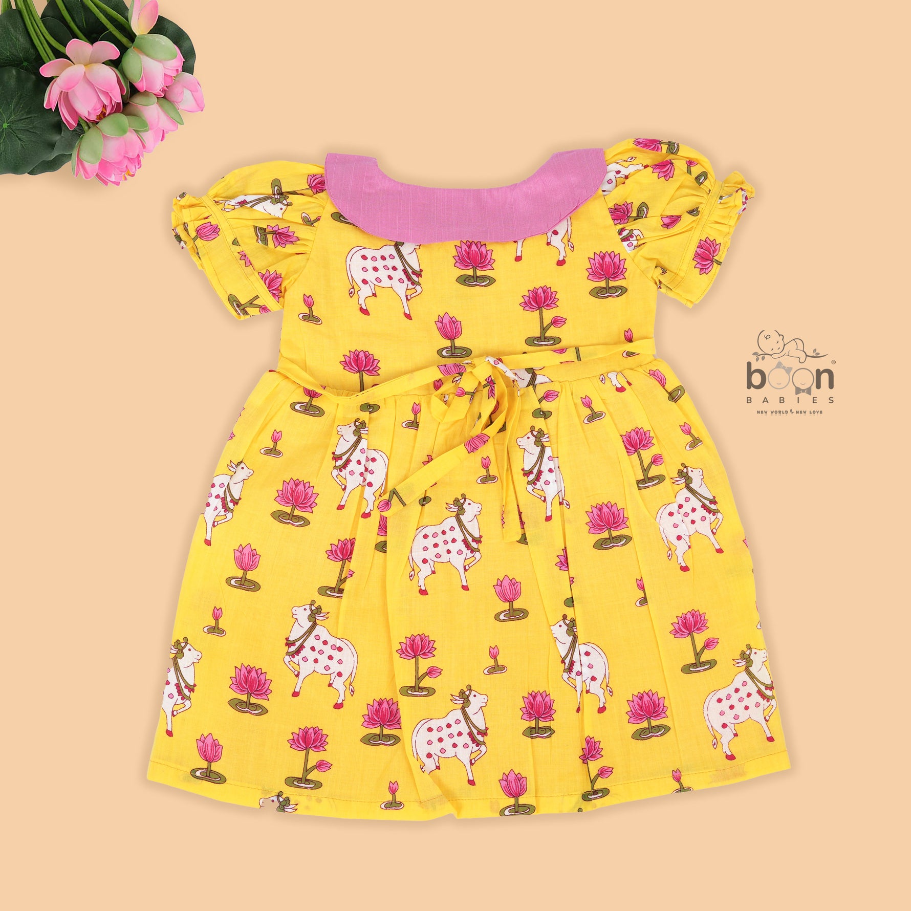 Yellow cotton puff frock with pink collar, bow tie & lotus print. Cute & comfy for girls aged 6M–4Y.