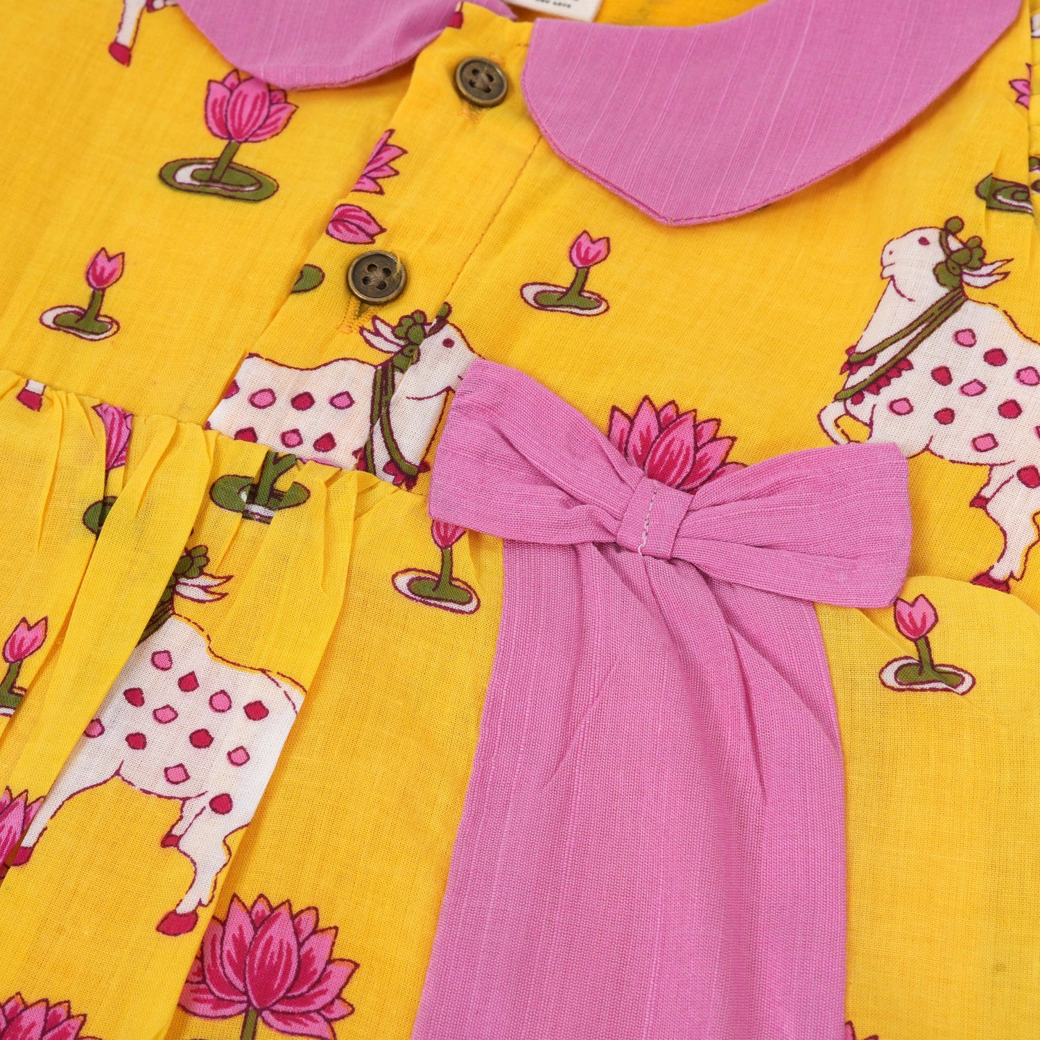 Yellow cotton puff frock with pink collar, bow tie & lotus print. Cute & comfy for girls aged 6M–4Y.