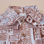 Boy wearing Boon Babies tribal printed cotton shirt with straight collar in earthy brown, featuring colorful tribal patterns.
