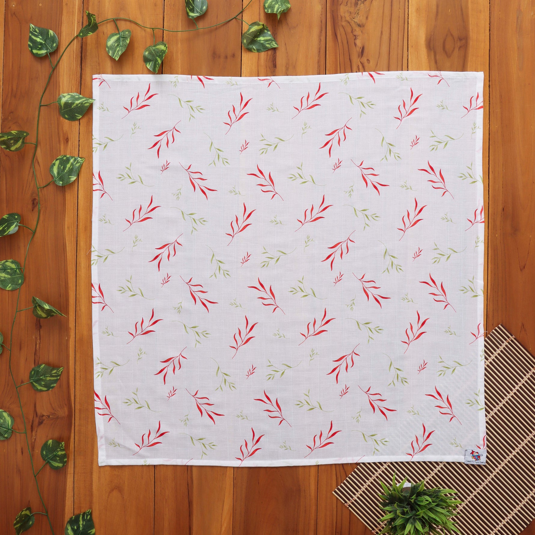 Soft muslin baby towel with red & green leaf print. 70x70 cm. Gentle on skin, perfect for newborn care.