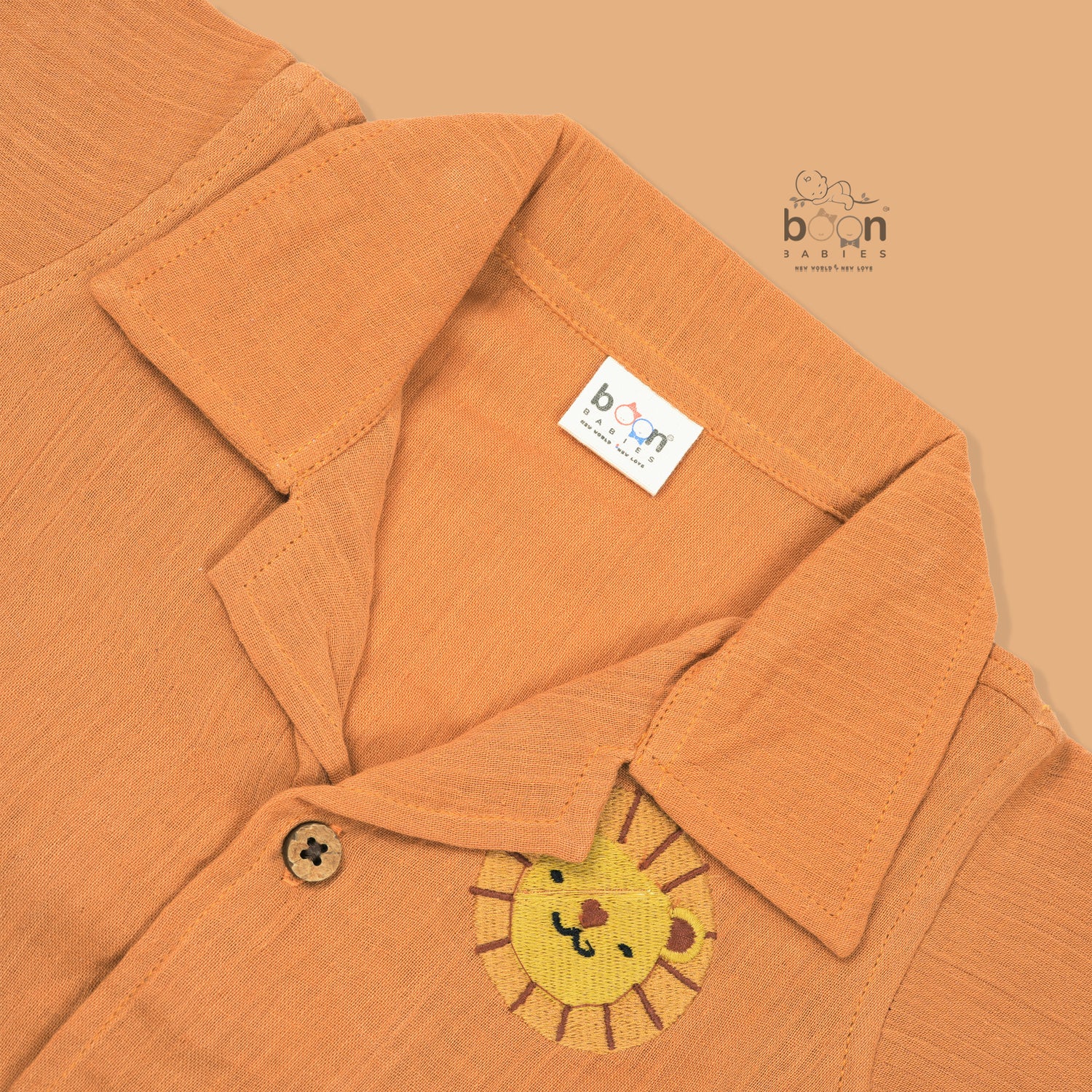 Orange crinkle muslin shirt and shorts set for boys with lion face embroidery, open collar, and elastic shorts – Boon Babies’ breathable summer wear from Coimbatore.
