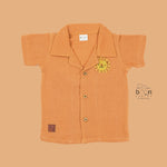 Orange crinkle muslin shirt and shorts set for boys with lion face embroidery, open collar, and elastic shorts – Boon Babies’ breathable summer wear from Coimbatore.
