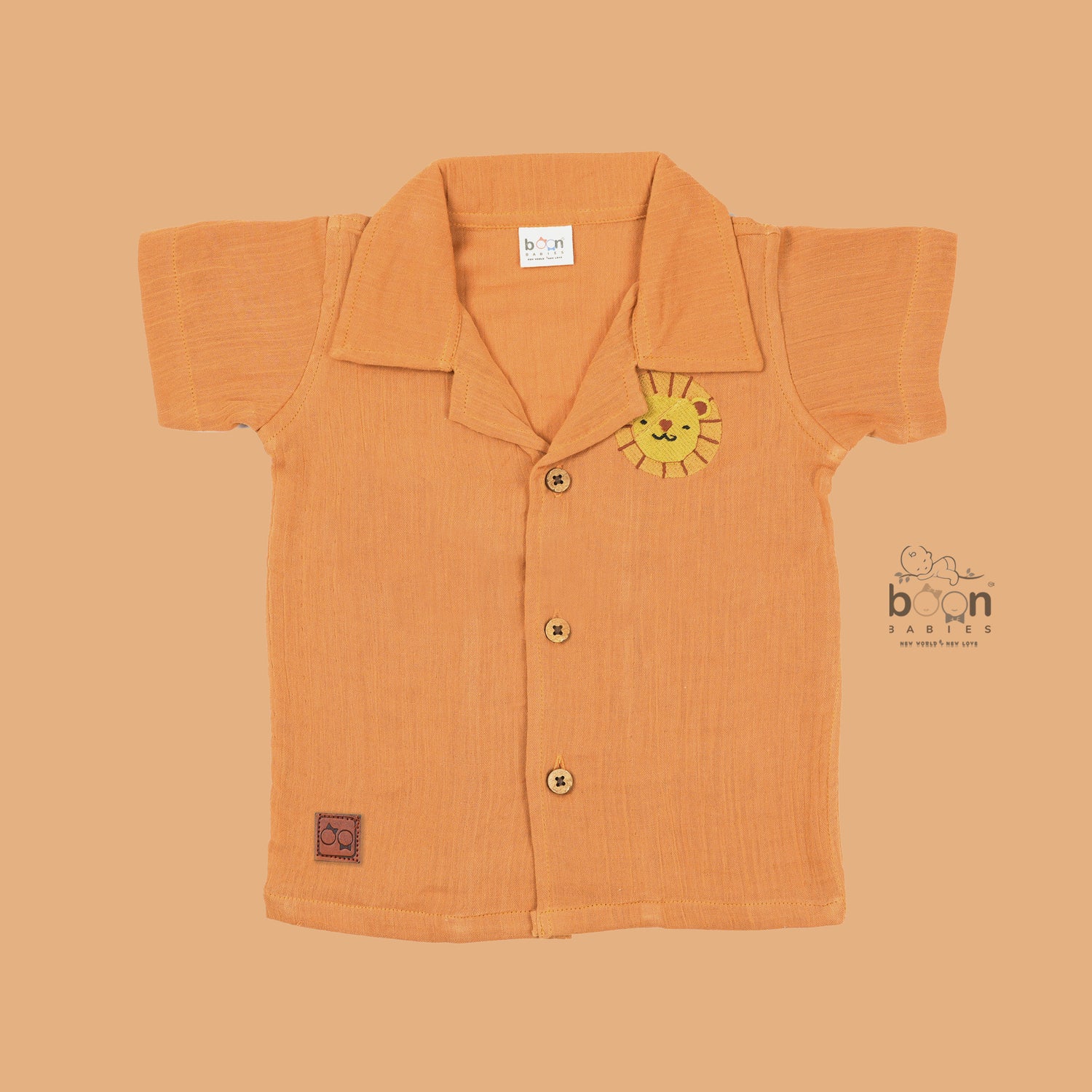 Orange crinkle muslin shirt and shorts set for boys with lion face embroidery, open collar, and elastic shorts – Boon Babies’ breathable summer wear from Coimbatore.

