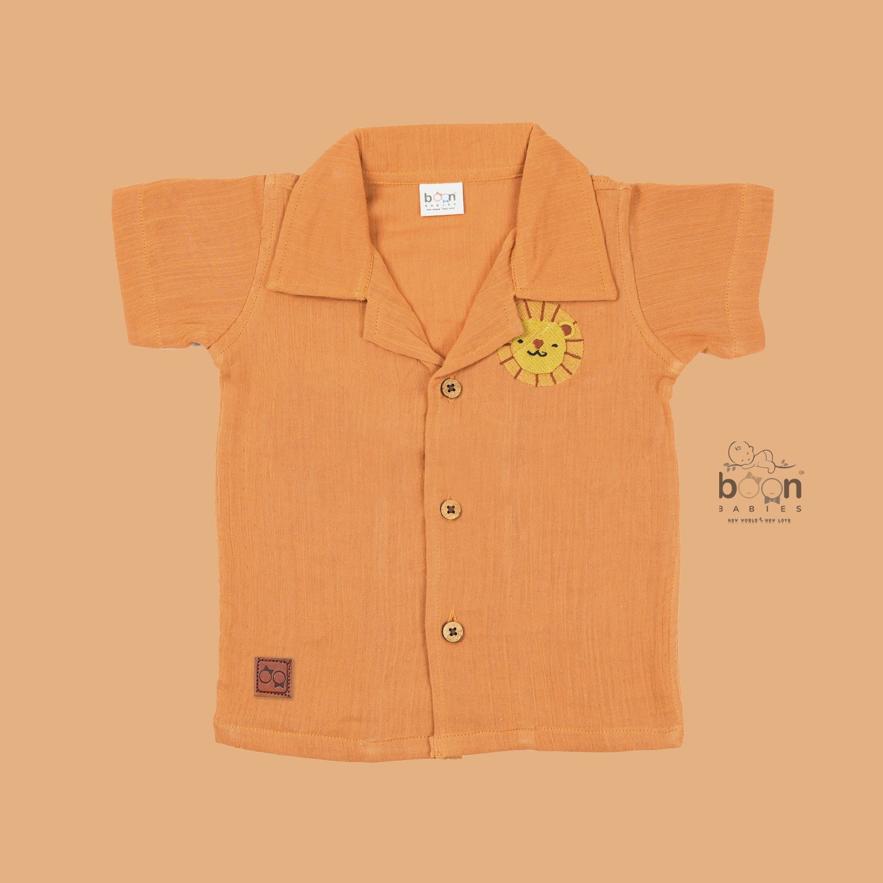 Orange crinkle muslin shirt and shorts set for boys with lion face embroidery, open collar, and elastic shorts – Boon Babies’ breathable summer wear from Coimbatore.
