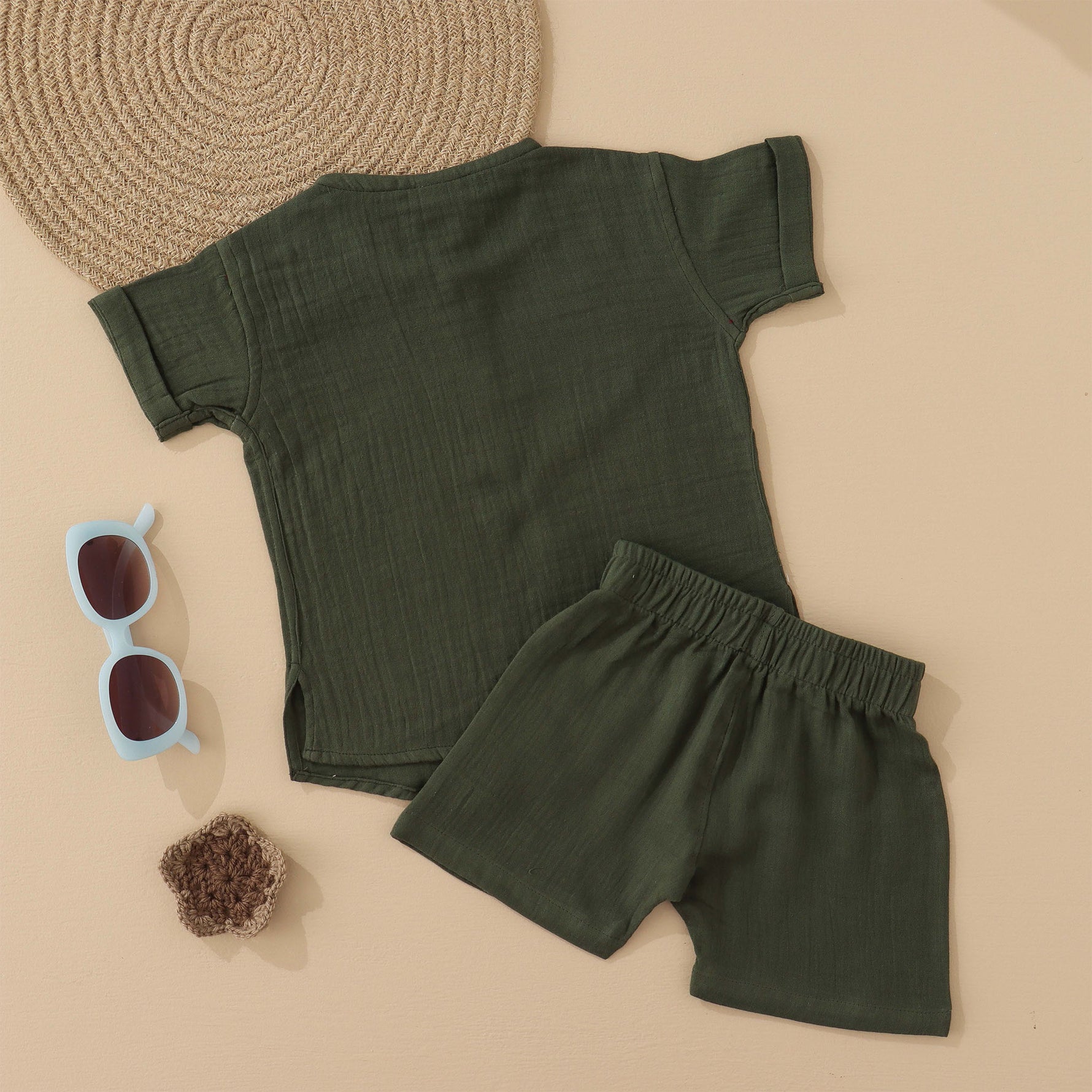 Dark olive green boys muslin co-ord with giraffe patch embroidery, round neck shirt with buttons, and elastic shorts – by Boon Babies, Coimbatore.
