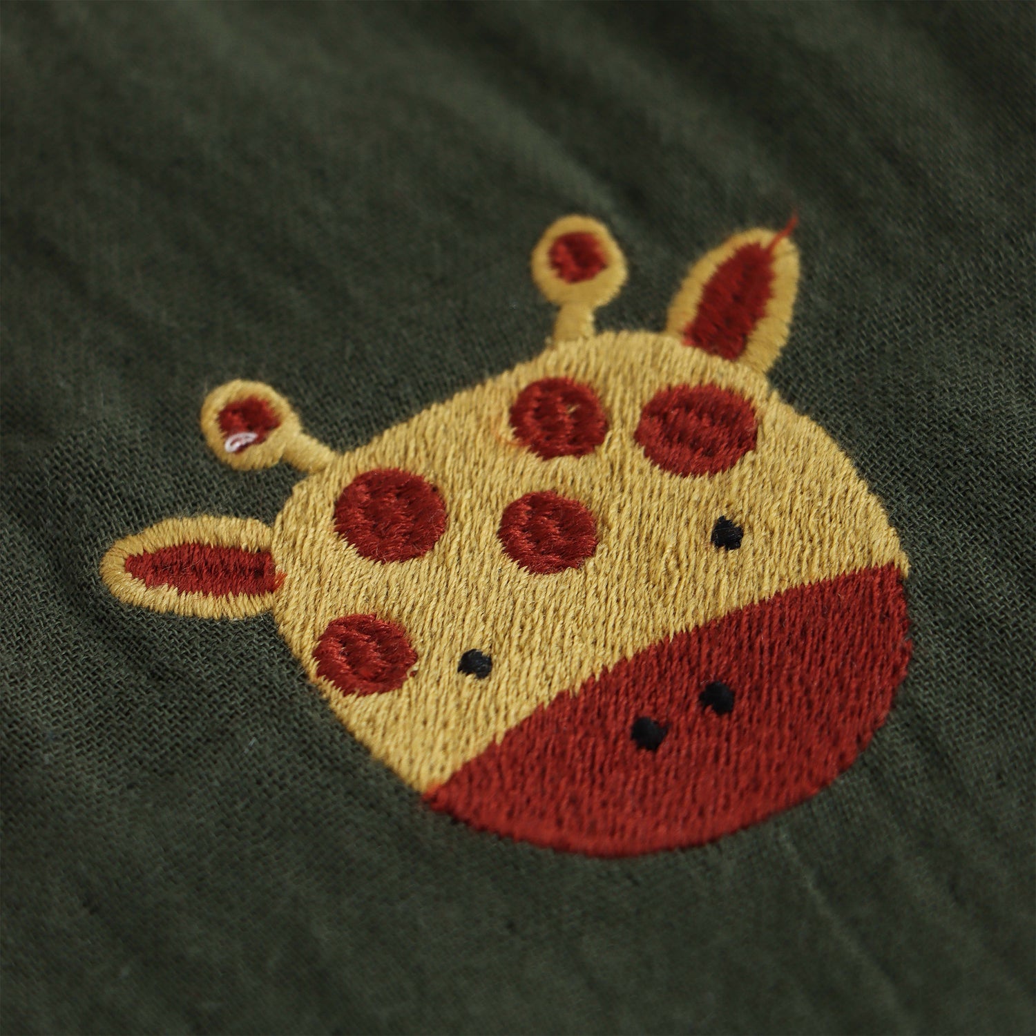 Dark olive green boys muslin co-ord with giraffe patch embroidery, round neck shirt with buttons, and elastic shorts – by Boon Babies, Coimbatore.
